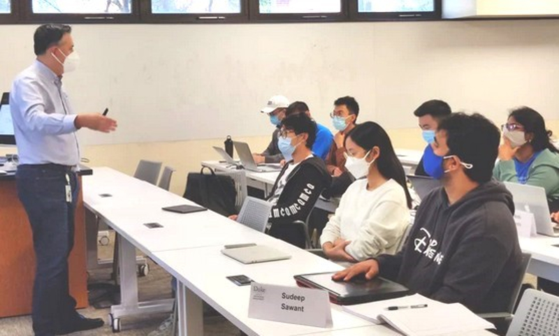 A teacher with a mask on in front of a classroom full of students with masks on