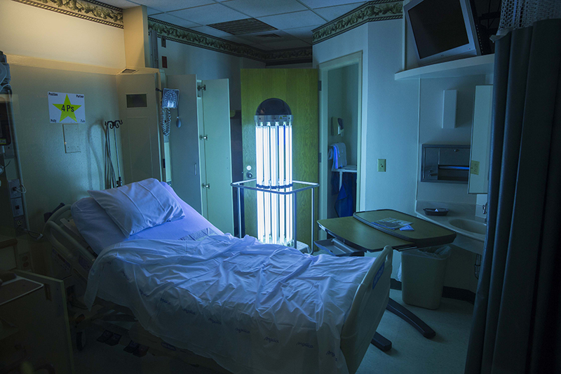 A hospital patient room with a tall cylindrical light in one corner
