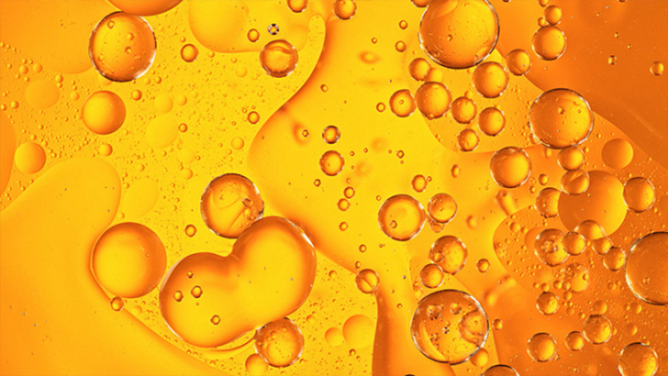 An orange liquid with lots of various sized circles floating within