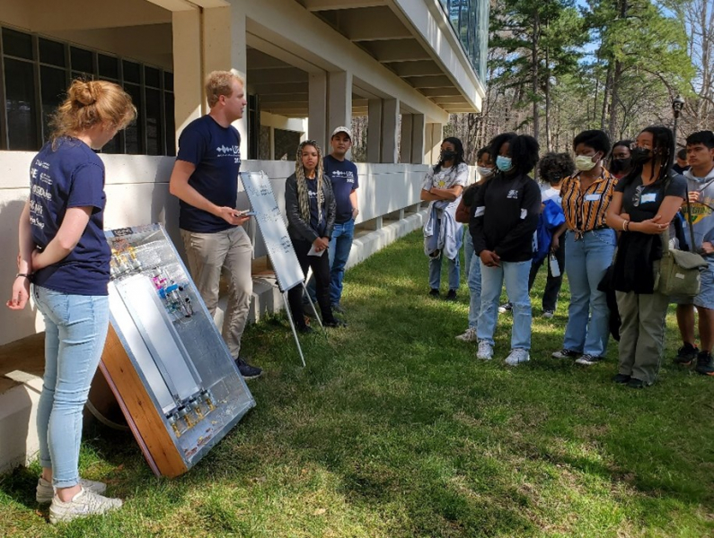 students demonstrating solar device to other students