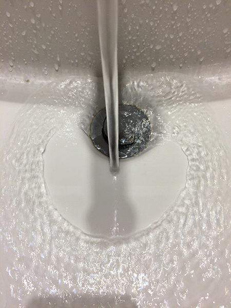 A smooth disc of water forms in the bottom of a sink.