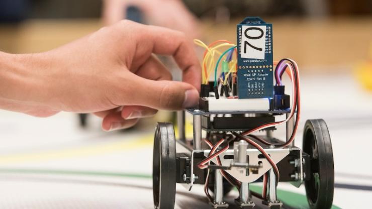 A student makes last-minute adjustments to his team's robot before final demonstrations