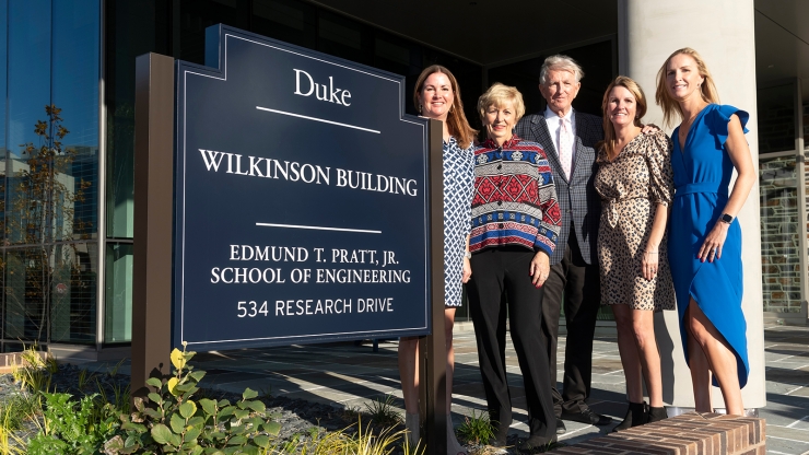 Wilkinson family with sign outside building