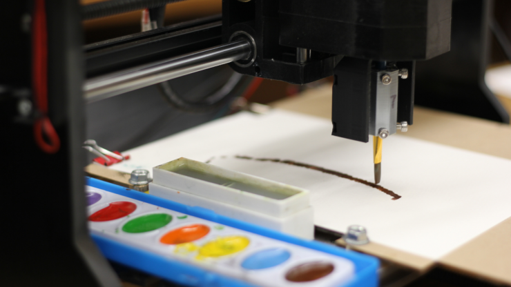 A CNC router redesigned to hold a paintbrush, with a tray of watercolors in the foreground