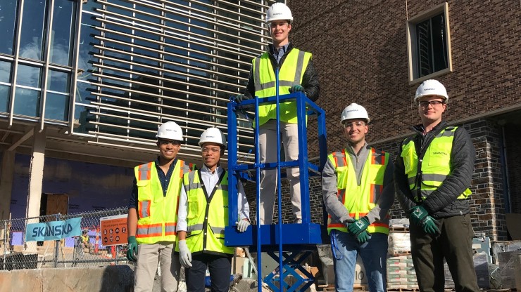 The scissor-lift safety device design team with their prototype across the street from where Skanska is construction Duke's newest engineering building.