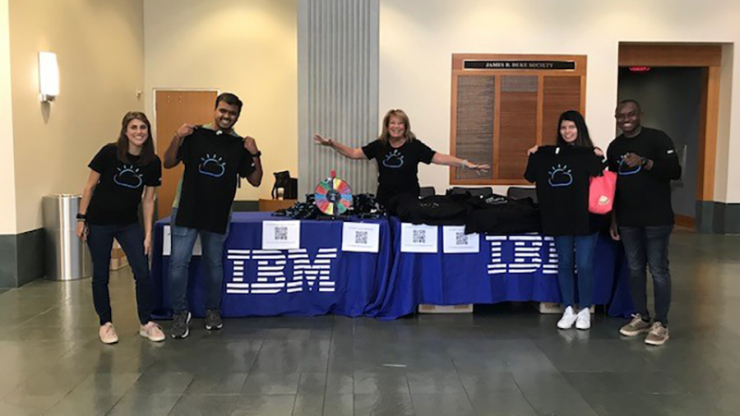 A group of people standing at a table with an IBM display