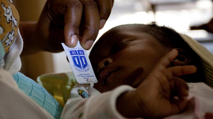 A woman in Tanzania gives her newborn baby antiretroviral drugs from a Pratt Pouch.