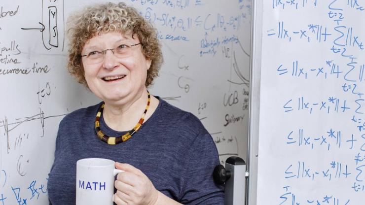 Ingrid Daubechies with math mug in front of white board with equations