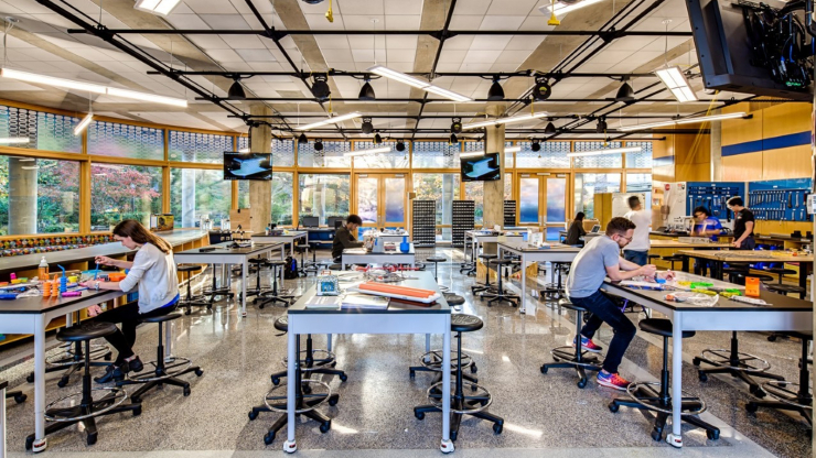 Duke Engineering’s Design POD is a 5,000-square-foot design space outfitted with workbenches, rapid prototyping machines such as laser cutters and 3-D printers, and various other power and hand tools that allow first-year students to gain knowledge about the engineering design process. A brightly lit work room full of tables and projects being worked on by students