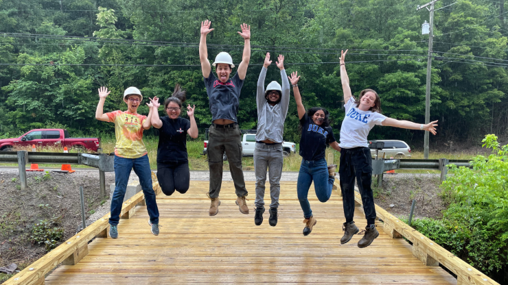 students jump into the air on a rural bridge
