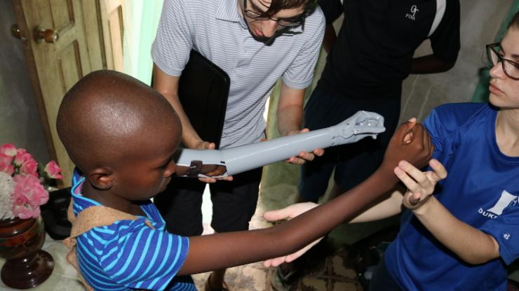 Emily Shannon and Gabriel Antoniak test the length of the first prototype prosthetic arm while the recipient tries it on during their first trip to Haiti
