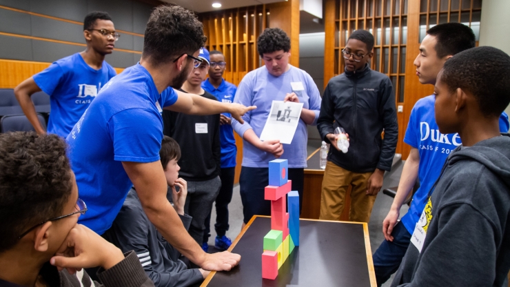 A group of people standing around colorful blocks on a table