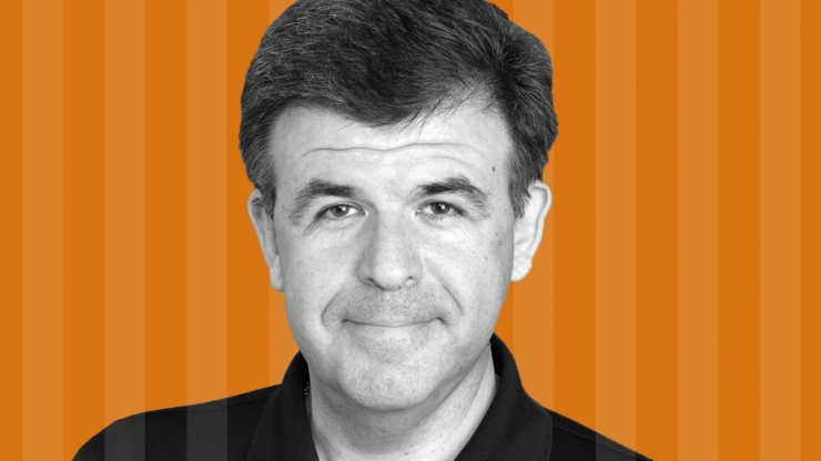 A headshot of a man in front of an orange background