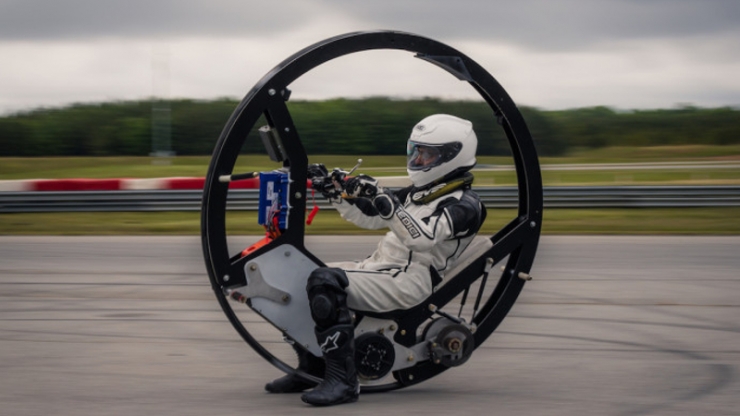 A person in a protective suit riding inside of a giant wheel