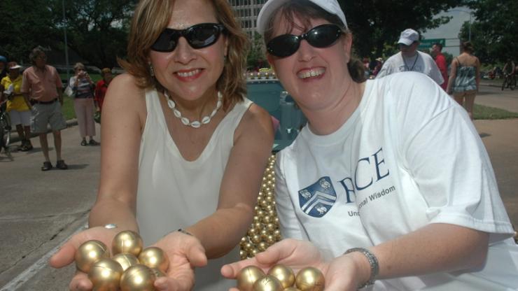 Naomi Halas and Jennifer West holding large golden spheres at a parade