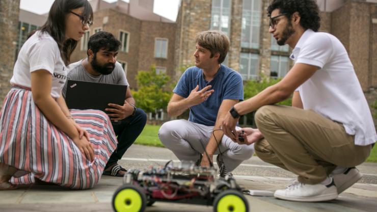 Miroslav Pajic kneeling with research group and small toy car