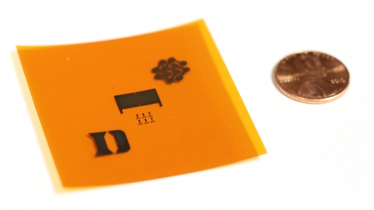A demonstration of the printed carbon nanotubes on a flexible surface. The prototype tire tread sensor (middle) is flanked by the logos of Duke University and Fetch Automotive Design Group. 