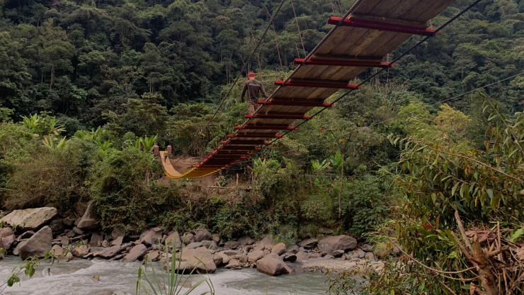 A hanging bridge over a river in a mountainous jungle area