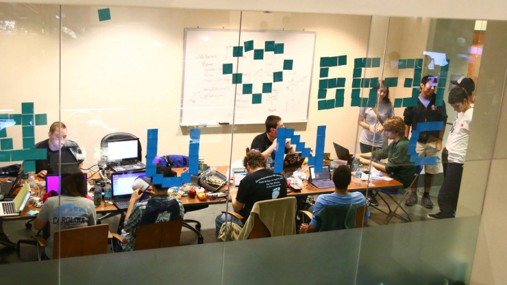 students working on a HackDuke project in a glass-walled room