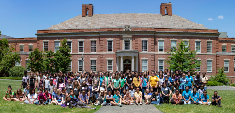A large group of women pose in front of Duke Engineering's Hudson Hall