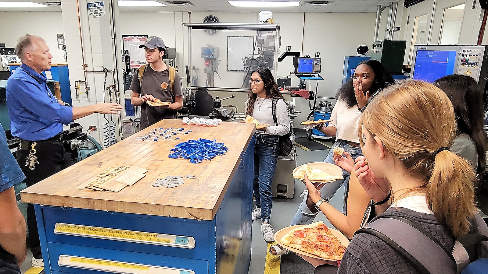a group of people in a room with machines and tables with pizza