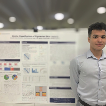 A young man standing next to a research poster