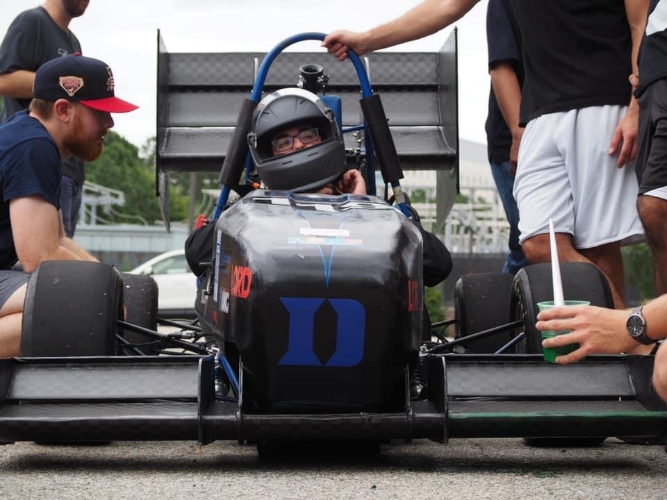 A student sitting in a racecar with a helmet on