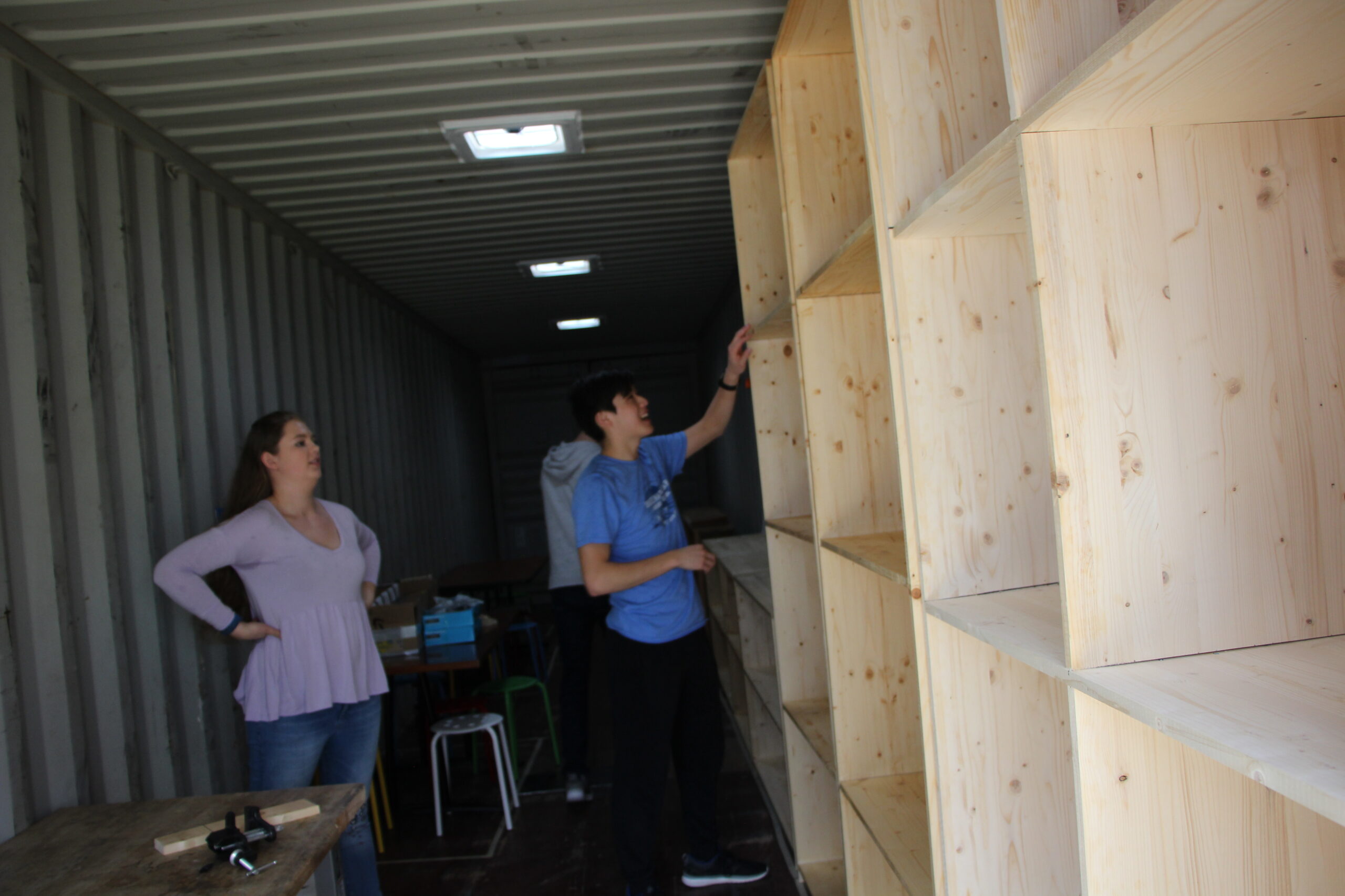 Students in the spring semester of Design 101 move shelves into a storage container, which will become a functioning design space. The team was recognized at the Global Innovation Challenge for their project.