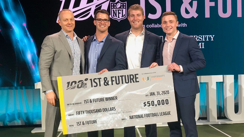 Four men standing with a giant check