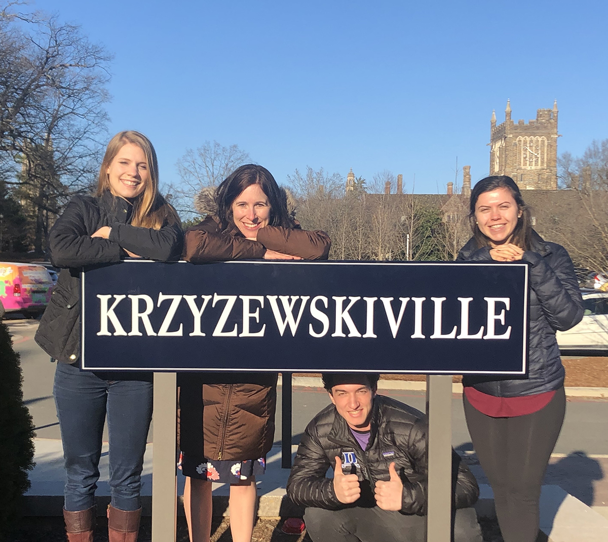 a group of people hang on a K-Ville sign outside of Duke