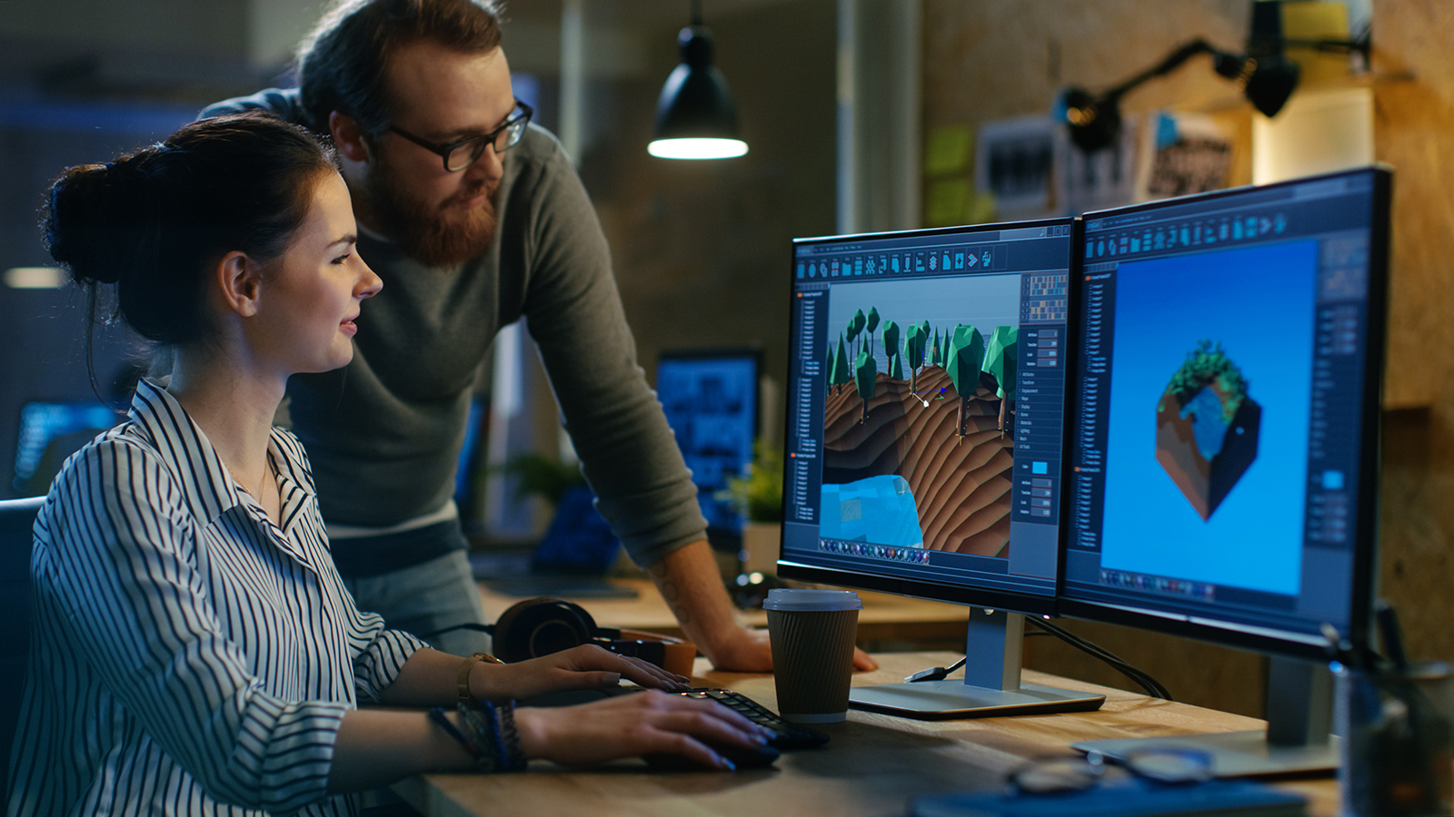 two people look at video screens in a game development lab