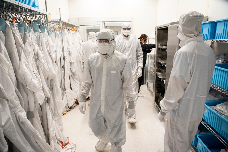 A line of people donning clean suits in a clean room lab