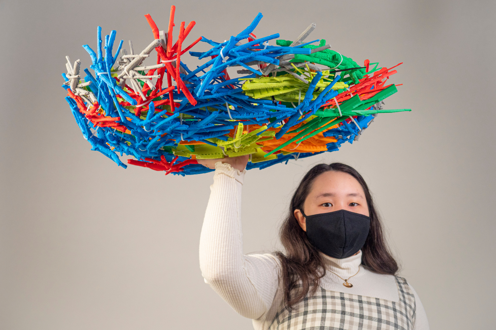 A young woman holding a large, multi-colored, plastic nest