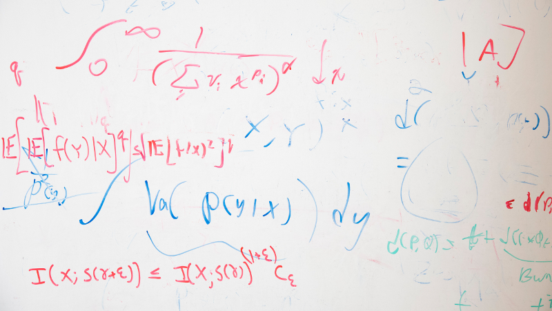 A dry-erase board with red and blue equations written all over it