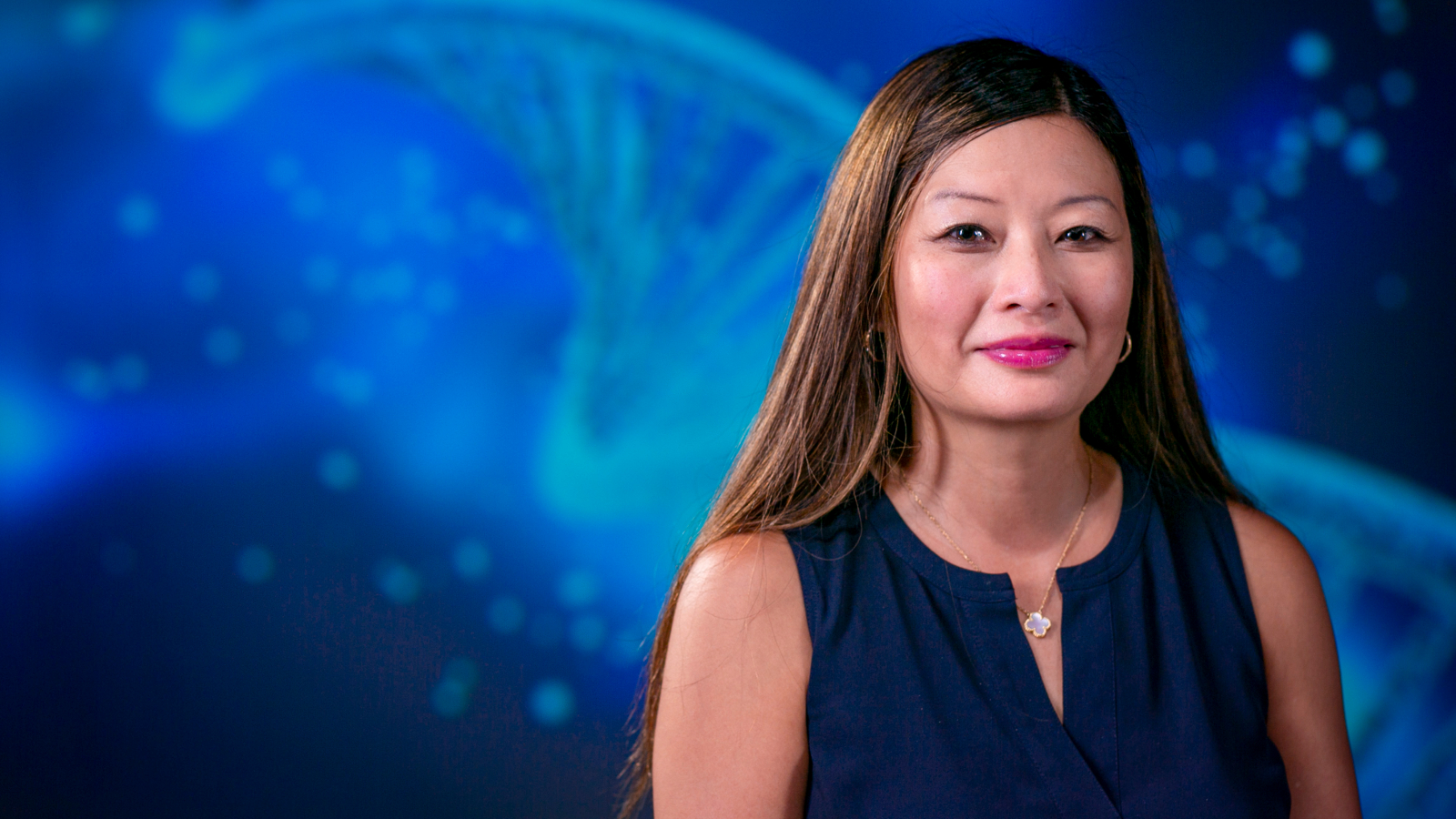 A woman in front of a blue background of helical DNA