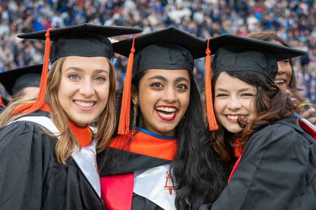 Three graduates of Duke University at commencement in cap and gown.