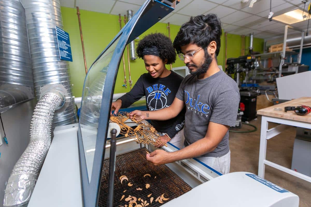 Duke University students work at a laser cutter in the Co-Lab Studio