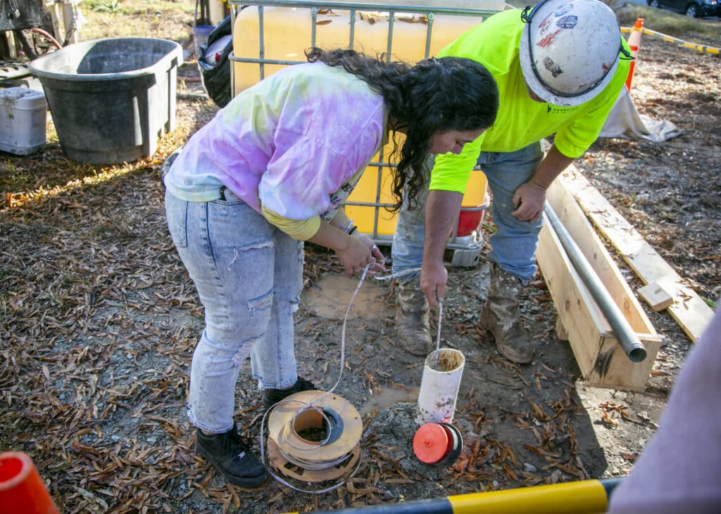 Two people look down a geothermal well at Duke University