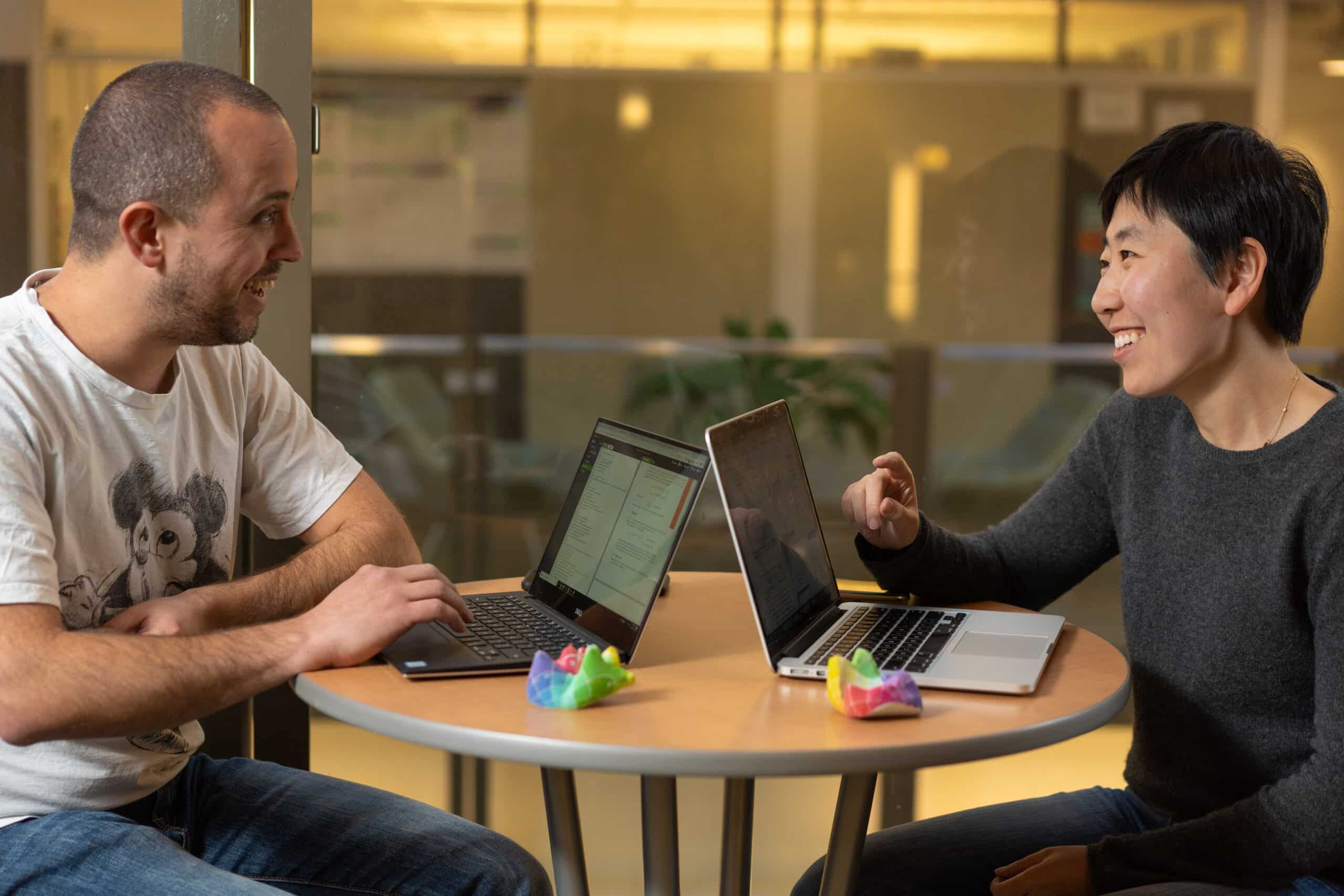 graduate students talk at a table with laptops open