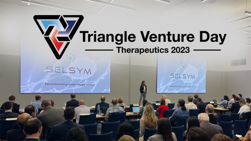 seated people listen to a person speak between two project screens overlaid with the text Triangle Venture Day Therapeutics 2023