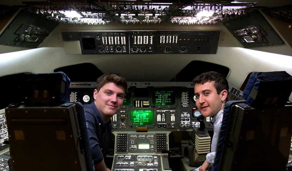 two male undergraduate students sitting in cockpit of space vehicle