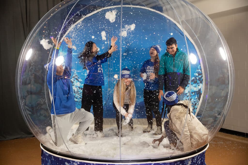 A group of people play in a life-sized snow globe.