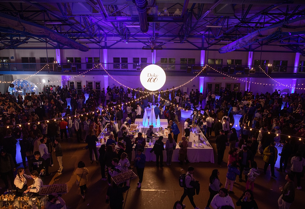 a disco ball and strung lights hang over a crowded dance floor