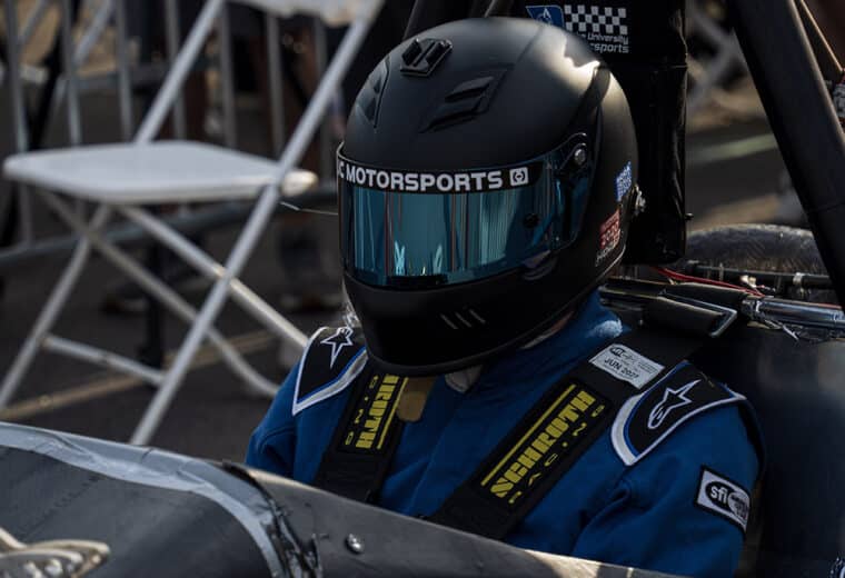 a person with a driving helmet on sitting in a small race car