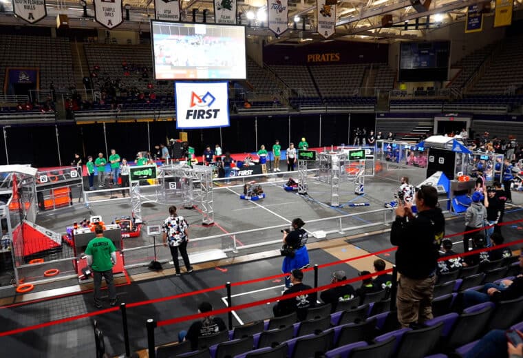 a large open concrete arena filled with robots and obstacles