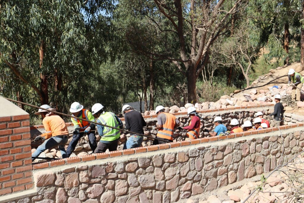 lots of people in hardhats pulling on a cable