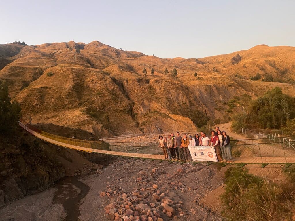 group of students standing on a long bridge with mountains behind