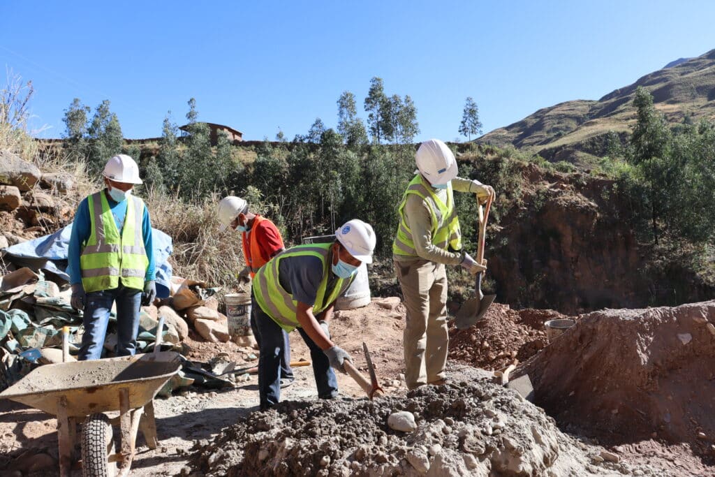 several workers in hardhats with bright vests and hand tools