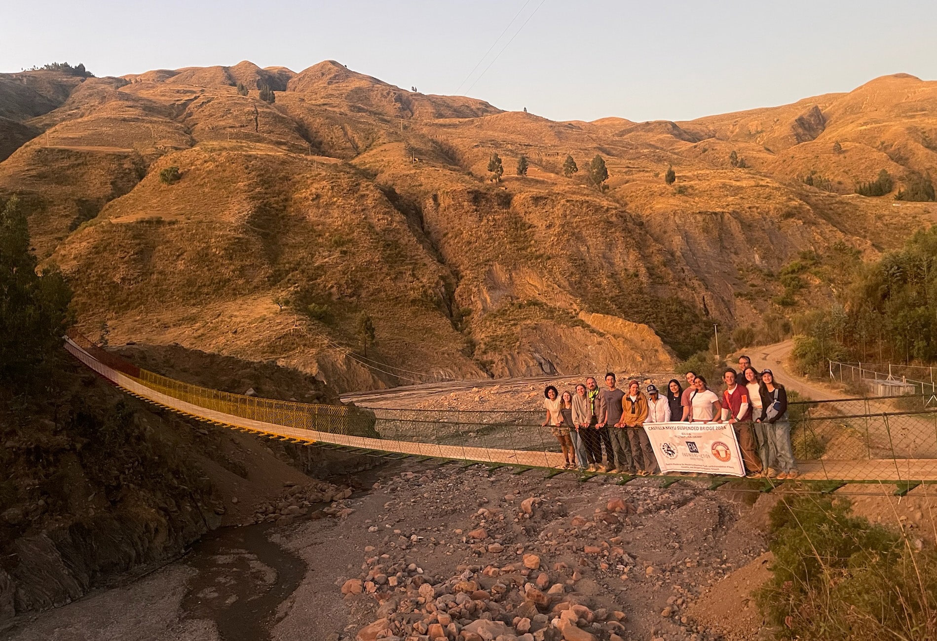 group of students on long bridge with mountains behind