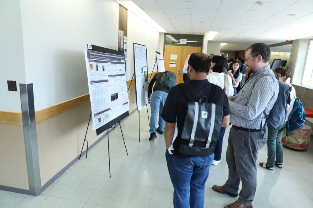 student gather around a poster board research presentation 